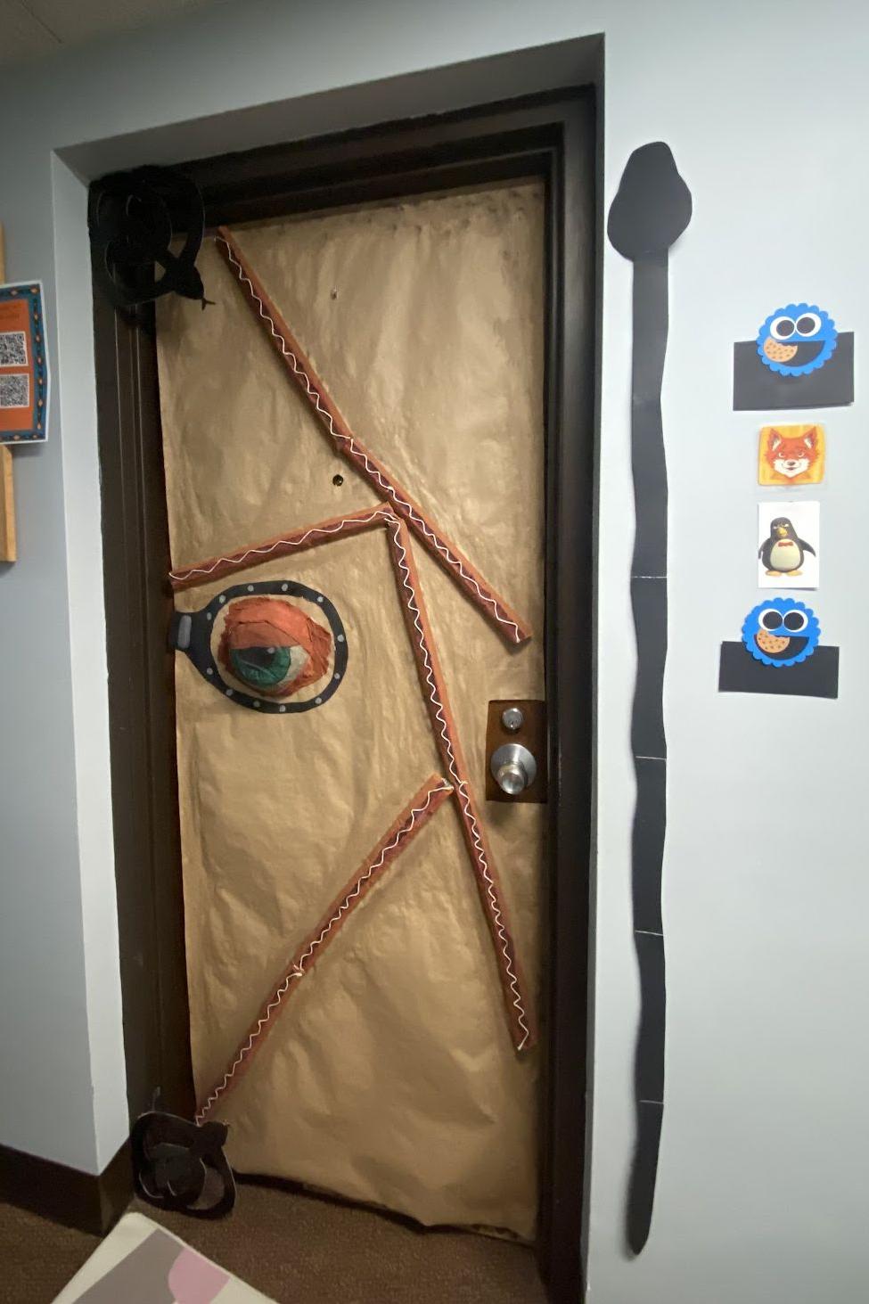 A dorm door with a patchwork of skin with an eye staring out.