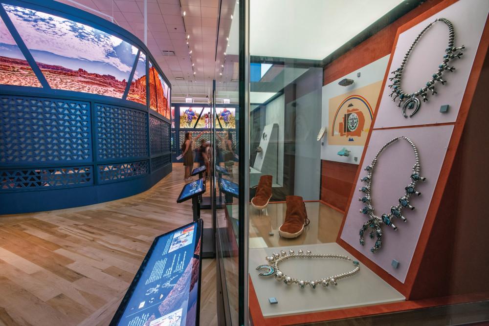 A display case at the 本机的真理 exhibit showing necklaces, footwear, and other items.