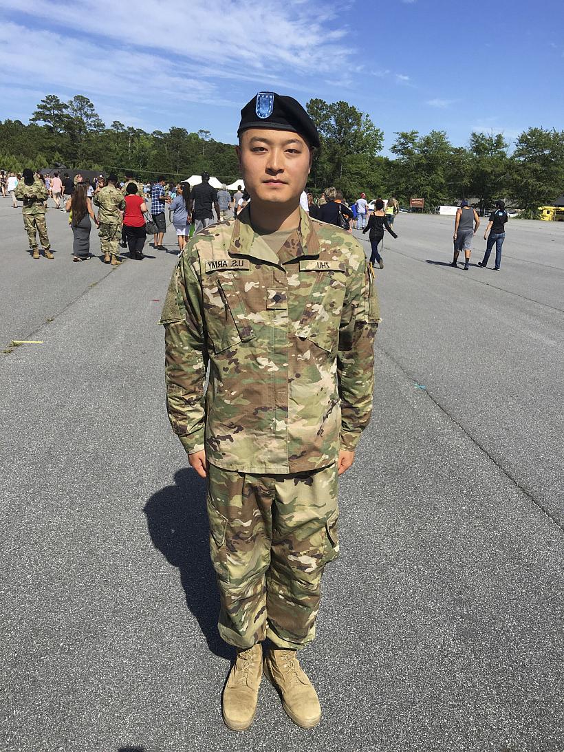 Xilong Tony Zhu'13 standing at attention in military garb.